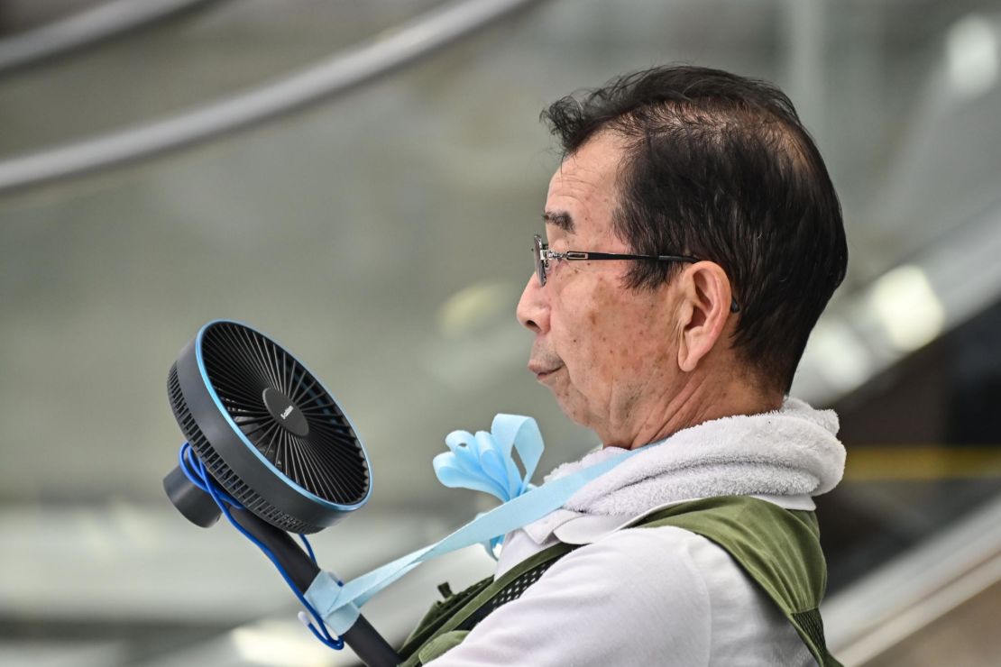 A man uses a fan to cool himself during a heat wave in Tokyo on August 17, 2020. 