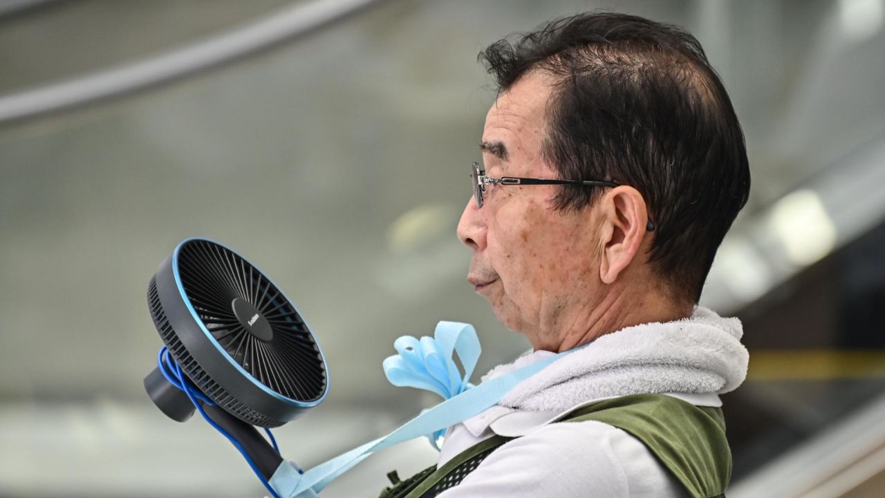 A man uses a fan to cool himself during a heat wave in Tokyo on August 17, 2020.