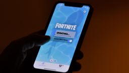 This illustration picture shows a person waiting for an update of Epic Games' Fortnite on their smartphone in Los Angeles on August 14, 2020. - Apple and Google on August 13, 2020 pulled video game sensation Fortnite from their mobile app shops after its maker Epic Games released an update that dodges revenue sharing with the tech giants. (Photo by Chris Delmas/AFP/Getty Images)