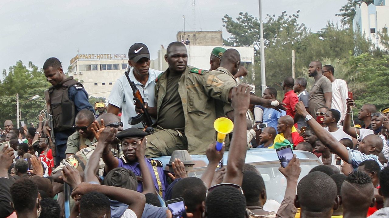 Armed Malian soldiers and policemen ride on the back of a pick-up truck as they arrive at Independence Square in Bamako on Tuesday following news of the coup.