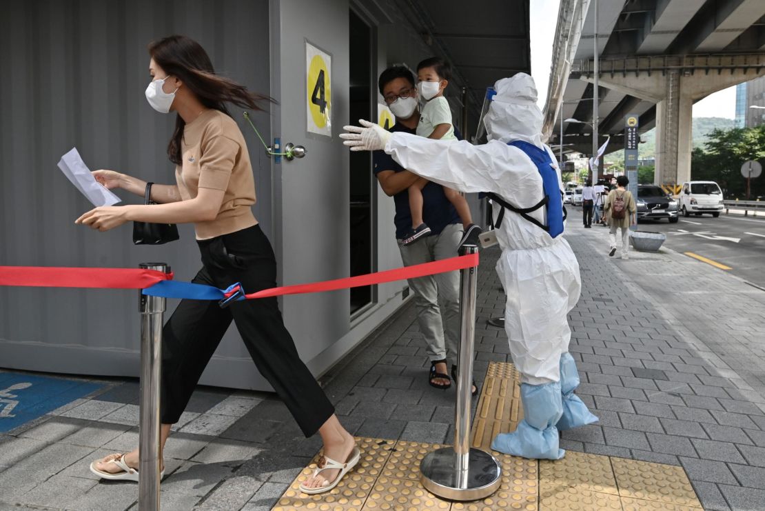 A health official wearing protective gear guides visitors at a Covid-19 coronavirus testing station in Seoul on August 18, 2020.