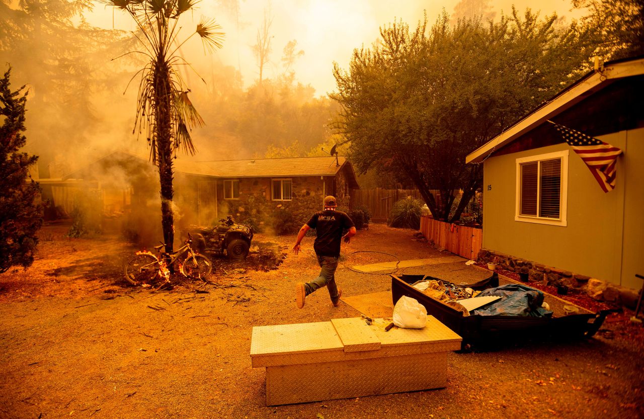 A resident runs into a home to save a dog while flames from the Hennessy Fire close in near Lake Berryessa on August 18.