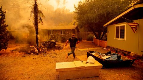 A resident runs into a home to save a dog while flames are getting close as a fire rages Tuesday near Lake Berryessa near Napa.