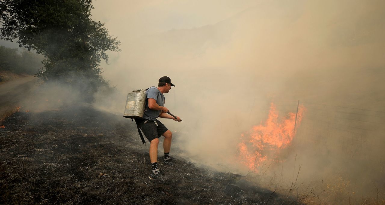 Tony Leonardini works on a spot fire as thunderstorm winds fan the Hennessy Fire in Napa County on August 17, 2020.
