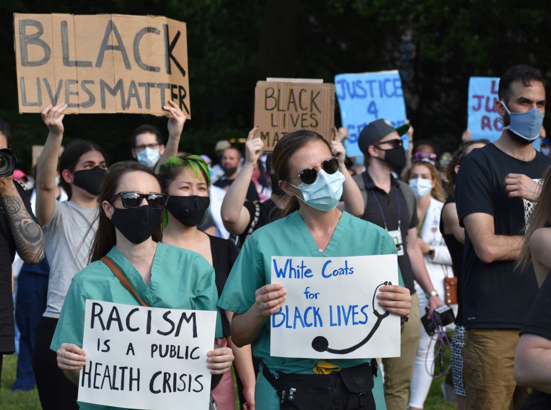 Medical workers hold signs during a rally, organized by a group named White Coats for Black Lives, on June 6 in New York.