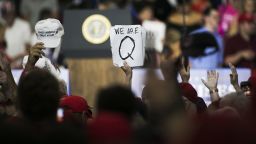 An attendee holds signs with the words "We Are Q" before the start of a rally with U.S. President Donald Trump in Lewis Center, Ohio, U.S., on Saturday, Aug. 4, 2018. Trump defended his use of tariffs that have inflamed tensions with China and Europe, telling an audience of diehard supporters on Saturday that playing hardball on trade is "my thing." Photographer: Maddie McGarvey/Bloomberg via Getty Images