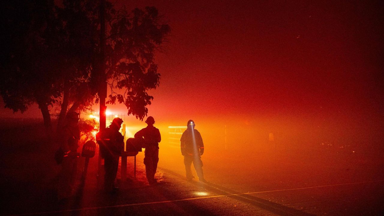 Firefighters keep an eye on flames as they approach a home in Vacaville, California.
