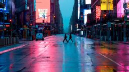 A couple wearing masks crosses the almost deserted Times Square on April 13, 2020 in New York City. - New York's governor declared April 13, 2020 that the "worst is over" for its coronavirus outbreak providing the state moves sensibly, despite reporting its death toll had passed 10,000. Andrew Cuomo said lower average hospitalization rates and intubations suggested a "plateauing" of the epidemic and that he was working on a plan to gradually reopen the economy. (Photo by Johannes EISELE / AFP) (Photo by JOHANNES EISELE/AFP via Getty Images)