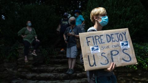 A group of protestors hold a demonstration in front of Postmaster General Louis DeJoy's home in Greensboro, North Carolina on August 16, 2020. - DeJoy has recently come under fire for what's perceived as steps ordered by the Trump administration to slow down the mail to help suppress absentee votes.