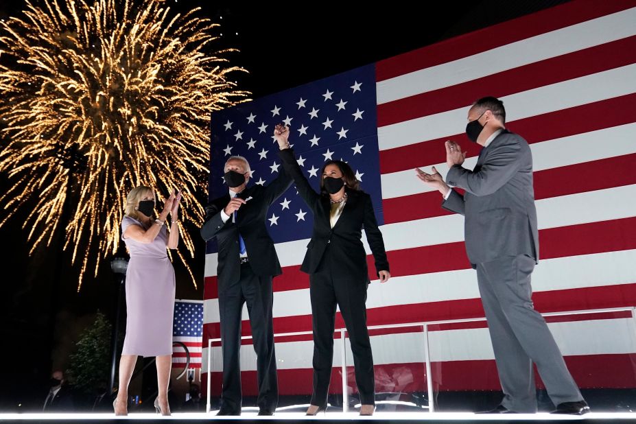 Biden joins hands with Harris after the <a href="https://www.cnn.com/2020/08/20/politics/gallery/democratic-convention-2020/index.html" target="_blank">Democratic National Convention</a> in August 2020. They are joined on stage by Biden's wife, Jill, and Harris' husband, Douglas Emhoff.