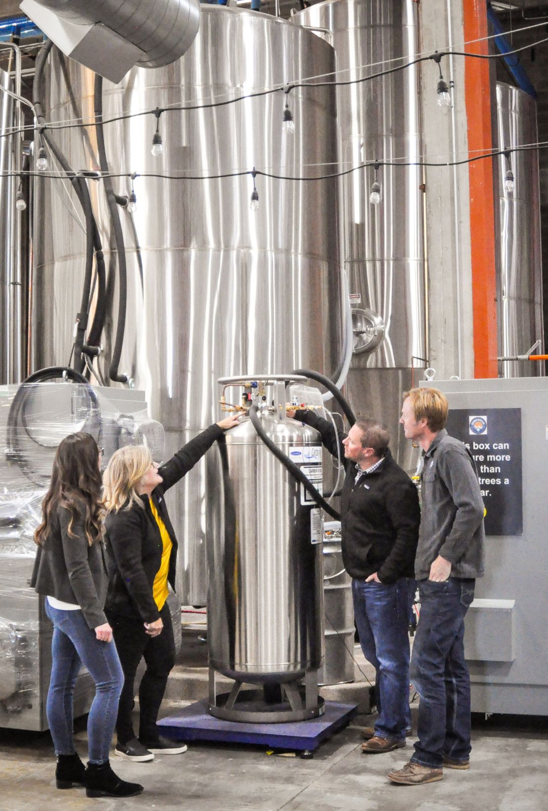 Kaitlin Urso (Colorado Department of Public Health and Environment), Amy George (Earthly Labs), Brian Cusworth (The Clinic) and Charlie Berger (Denver Beer) checking the valves for Denver Beer's CO2 tank and Earthly Labs' CO2 recovery equipment that will later be used in The Clinic's cannabis plants.