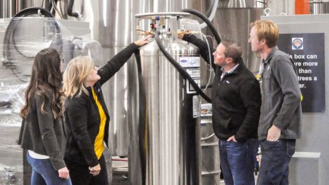 Kaitlin Urso (Colorado Department of Public Health and Environment), Amy George (Earthly Labs), Brian Cusworth (The Clinic) and Charlie Berger (Denver Beer) checking the valves for Denver Beer's CO2 tank and Earthly Labs' CO2 recovery equipment that will later be used in The Clinic's cannabis plants.