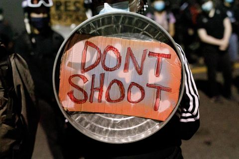 A demonstrator uses a shield for protection on August 19.
