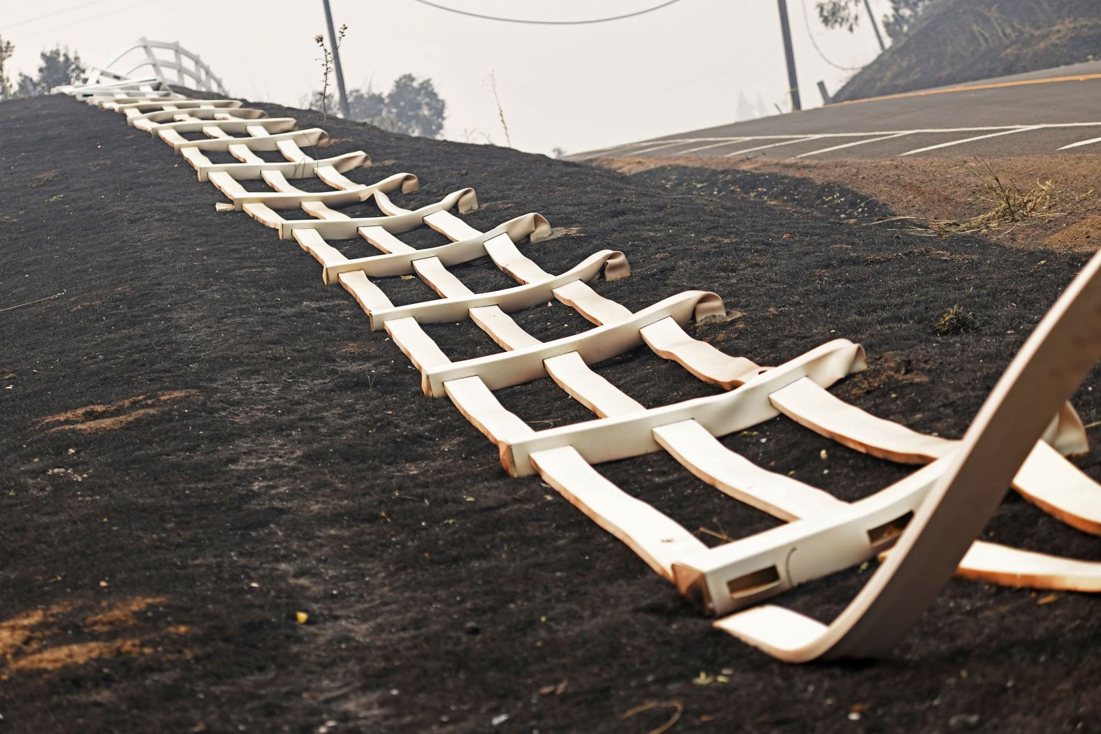 A melted plastic fence lies on the charred ground after fire swept through Vacaville on August 20, 2020.