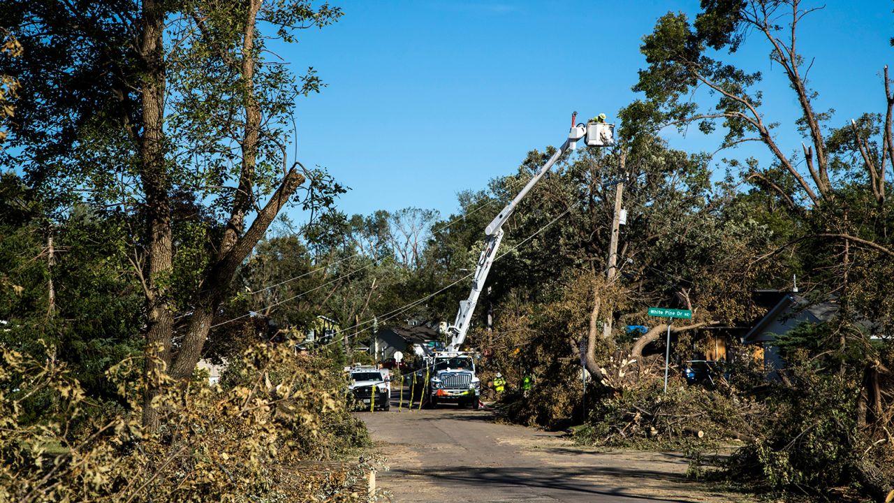 Tree branches pile up along the street as power line crews with Alliant Energy work to repair electrical lines on  Tuesday, August 18, 2020, in Cedar Rapids, Iowa.