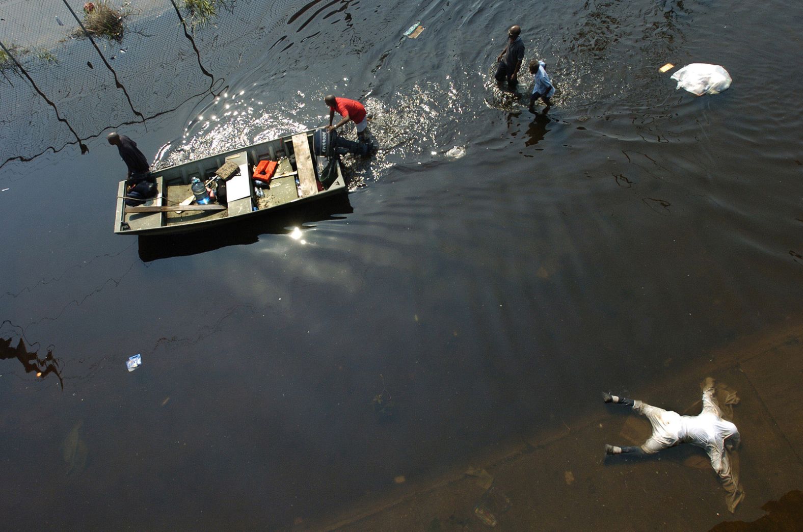 A dead body is seen in the foreground as people push a boat outside the Superdome on September 2, 2005.