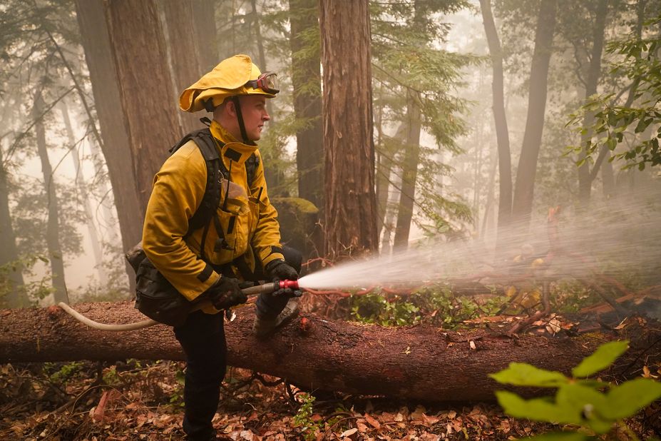 Karol Markowski of the South Pasadena Fire Department hoses down hot spots while battling the CZU Lightning Complex fires in Boulder Creek, California, on August 22, 2020.
