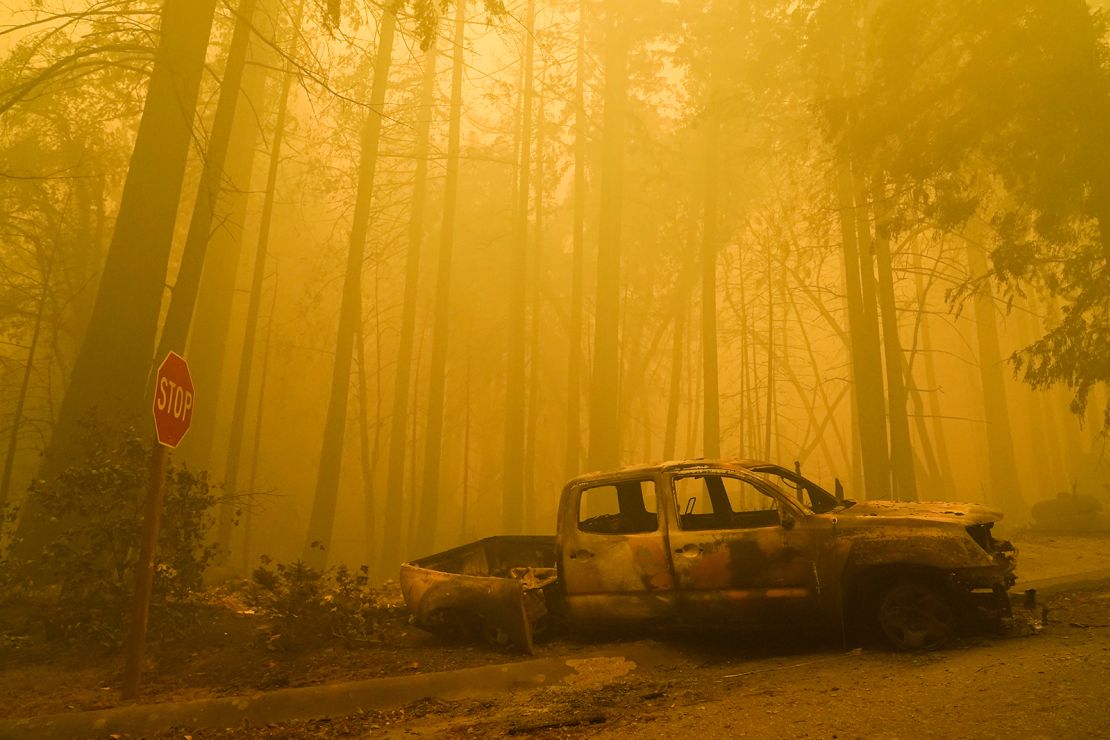 A burned out vehicle is left in front of a fire- ravaged residence as smoke fills the sky on Saturday, August 22, in Boulder Creek, California.