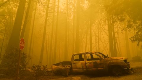 A burned out vehicle is left in front of a fire- ravaged residence as smoke fills the sky on Saturday, August 22, in Boulder Creek, California.