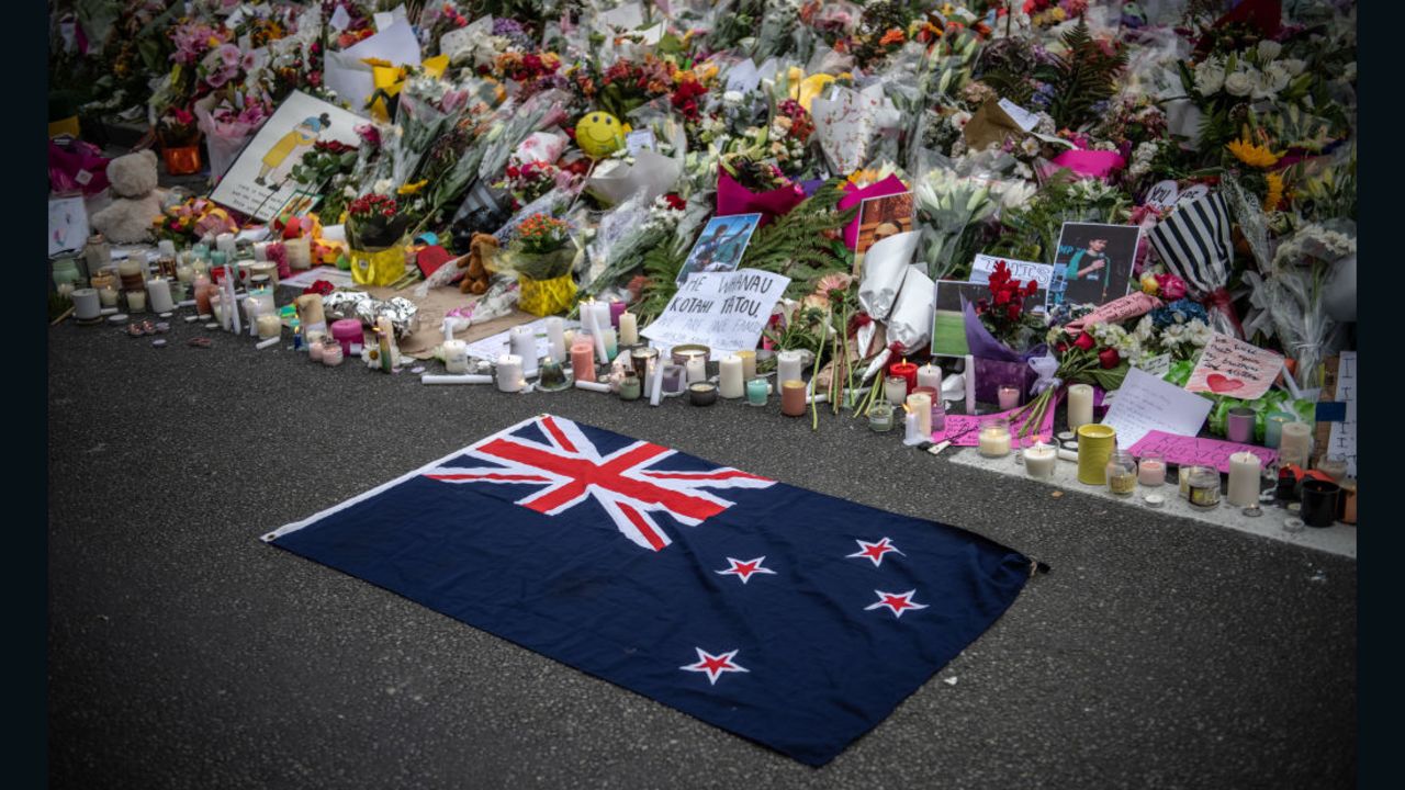 A New Zealand flag is placed next to flowers and tributes near Al Noor Mosque on March 18, 2019 in Christchurch, New Zealand.