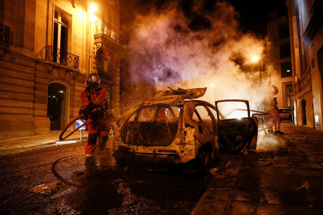 Firefighters extinguish a burning car near the Champs-Élysées following PSG's Champions League final defeat.
