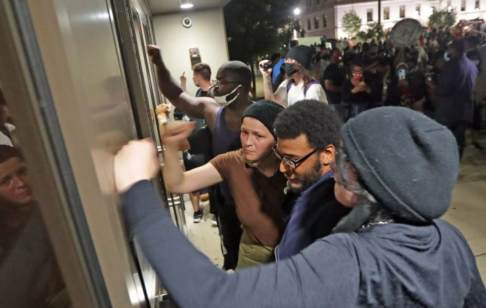 People pound on the door of the Kenosha Police Department.