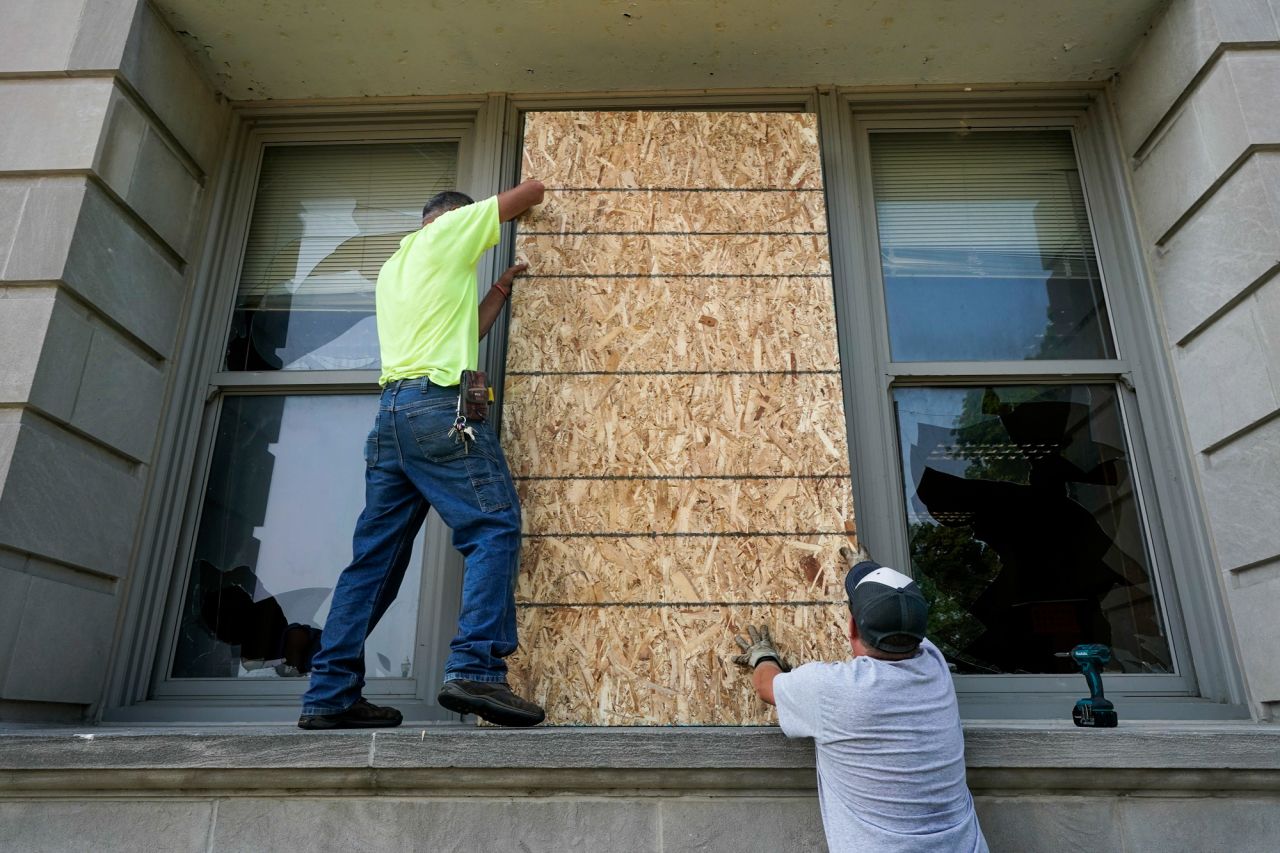 Joe Loewen and Dan Noonan put boards over a broken window at the Harborside Academy. The windows were broken during protests on Sunday, August 23