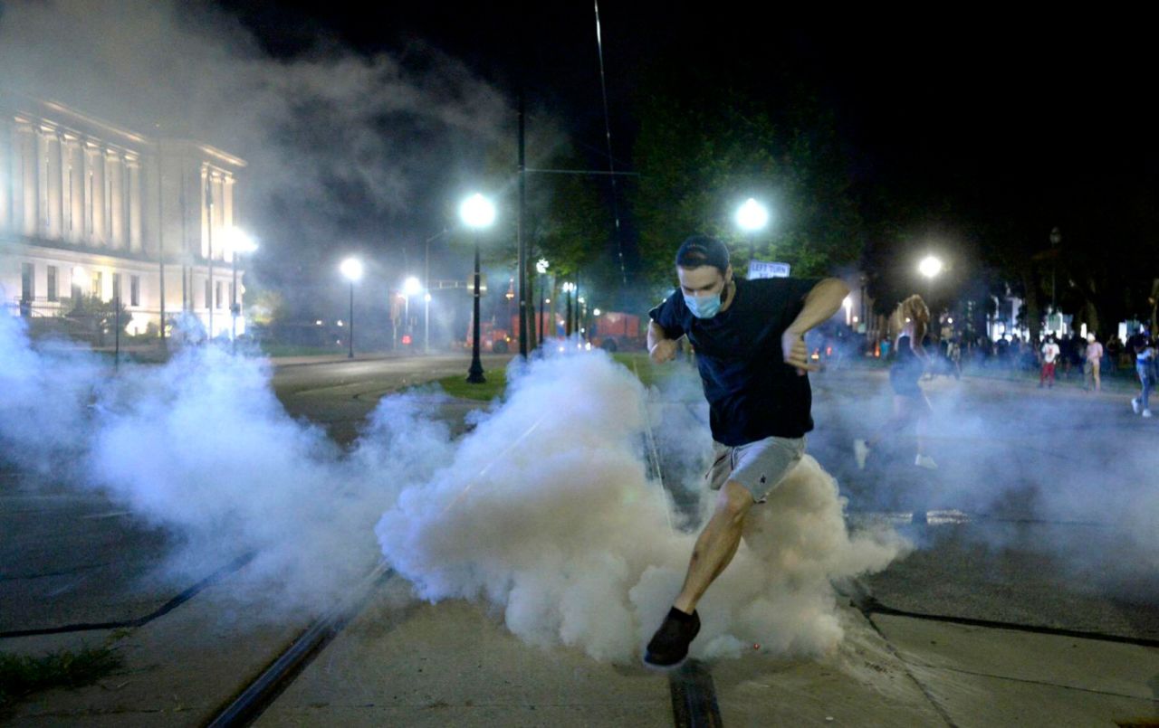 A man jumps over a tear-gas canister as he is fired upon with rubber bullets on August 23.