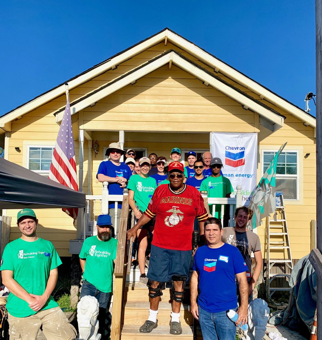Felix Lewis, a Vietnam veteran, poses in front of his newly renovated home with volunteers from Chevon who helped complete the work.