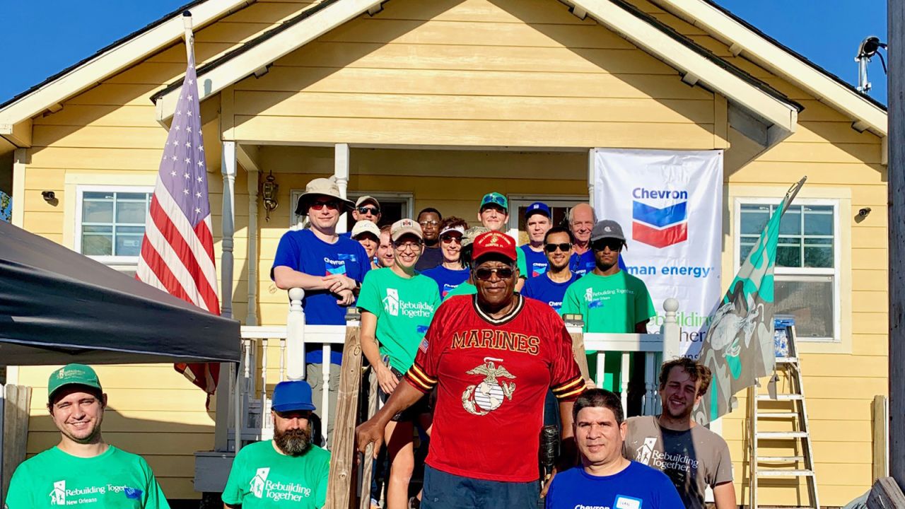 Felix Lewis, a Vietnam veteran, poses in front of his newly renovated home with volunteers from Chevon who helped complete the work.