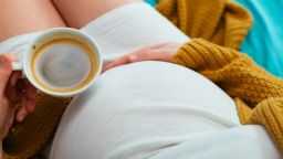 Pregnant woman drinking coffee. Aerial close up view.