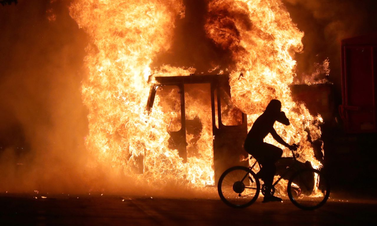A man rides a bike past a city truck that was set on fire on August 23.