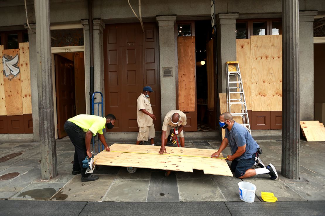 Workers board up windows in New Orleans' French Quarter before tropical storms Marco and Laura.