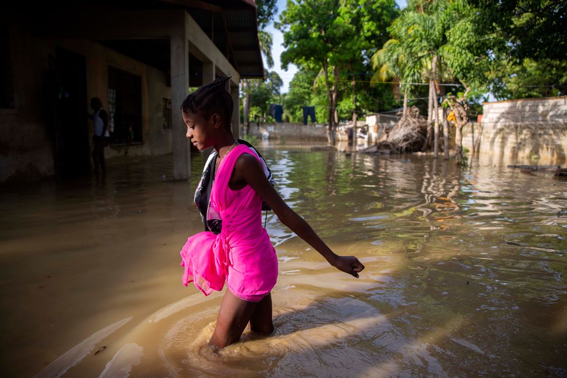 A girl wades toward her flooded home Monday after Tropical Storm Laura hit Port-au-Prince, Haiti.