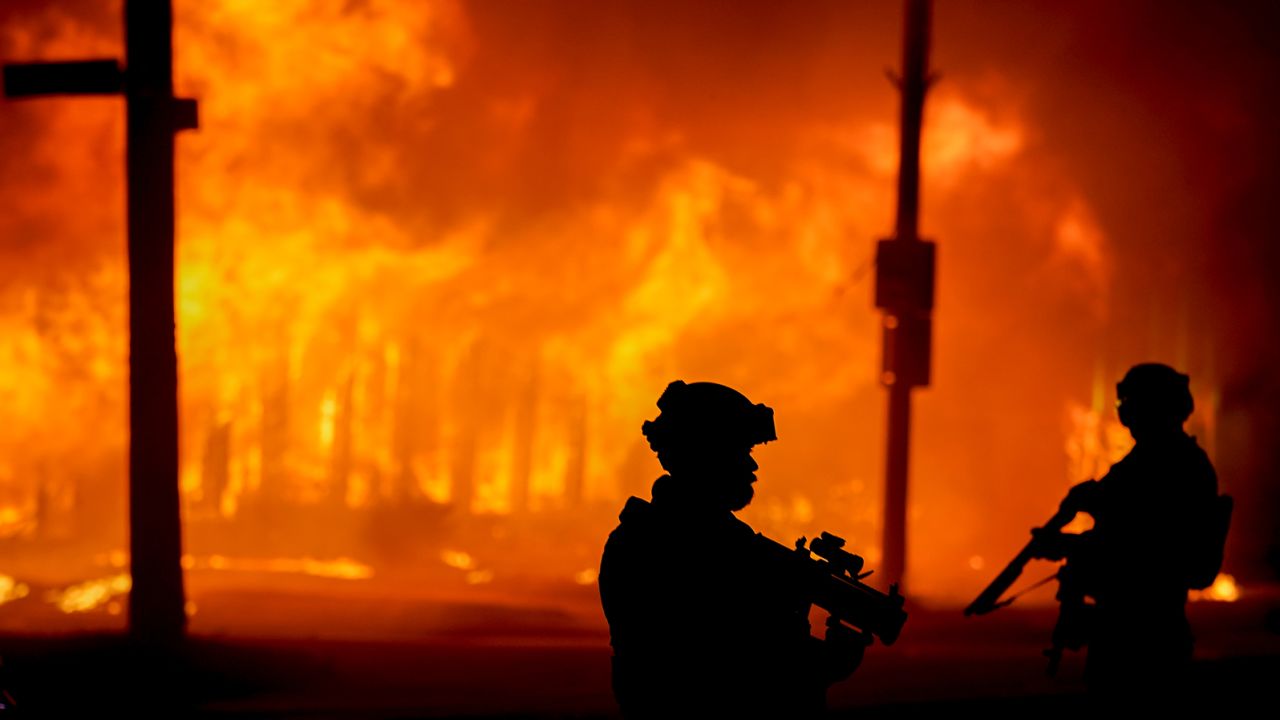 Police stand near a building that was on fire during protests Monday in Kenosha