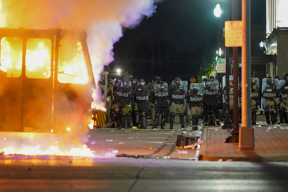 Police stand near a garbage truck ablaze during protests Monday in Kenosha.