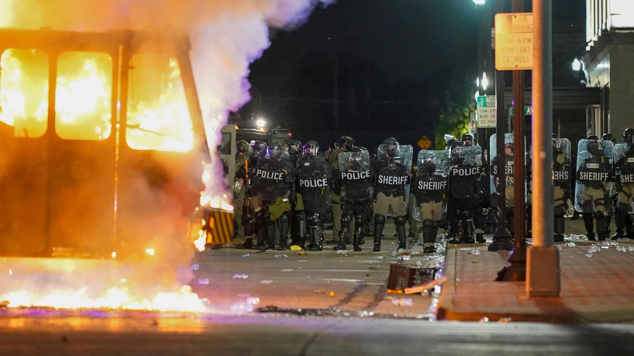 Police stand near a garbage truck ablaze during protests Monday in Kenosha.