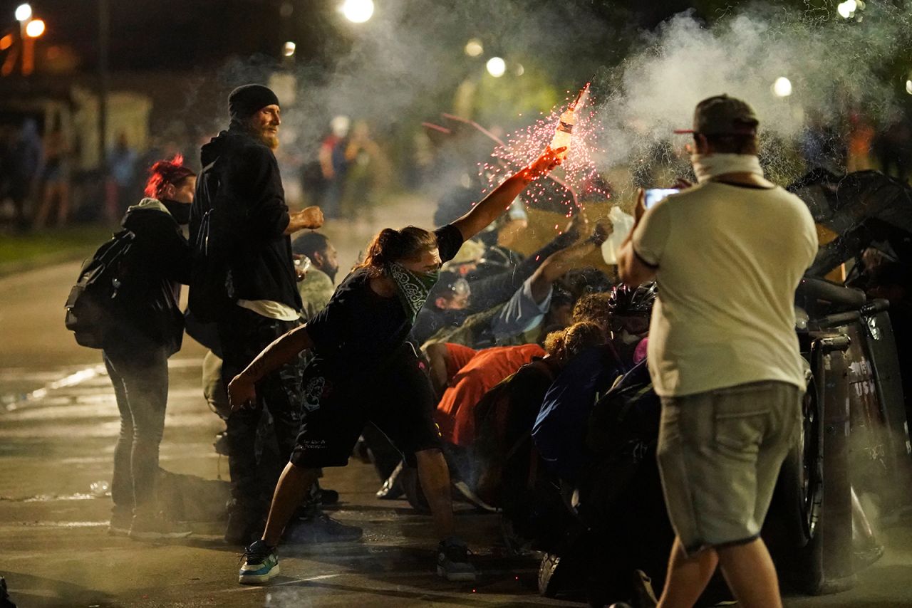 A protester tosses an object toward police during clashes outside the Kenosha County Courthouse on August 25.