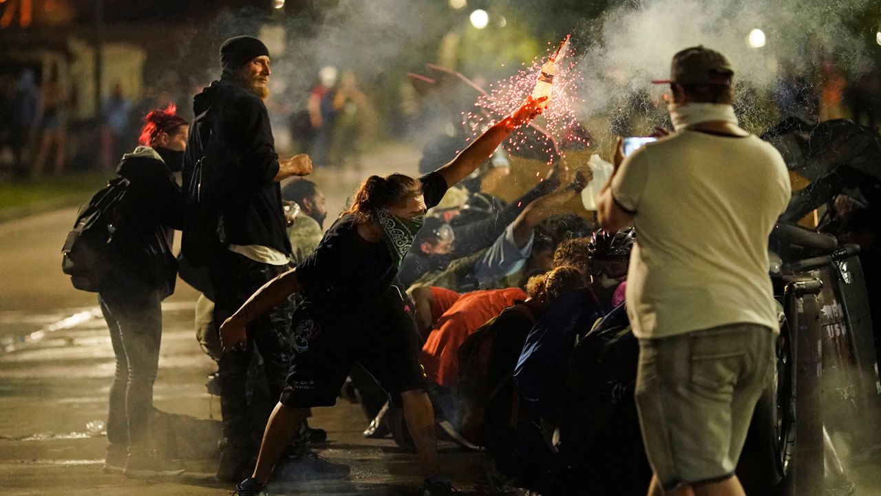 A protester tosses an object toward police during clashes outside the Kenosha County Courthouse late Tuesday in Kenosha