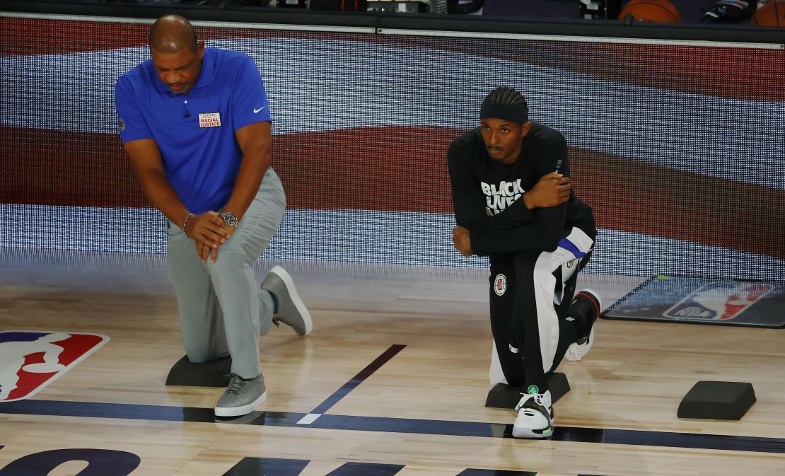 Rivers kneels with Lou Williams  during the National Anthem before the start of a game against the Dallas Mavericks.