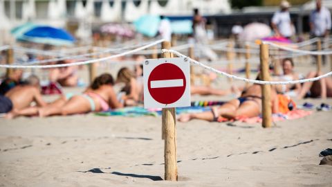 A no entry sign is attached to a wooden pilar at 'Couchant or Sunset beach', as sunbathers sit or lie in roped off distancing zones marked out by the municipality along the beach in La Grande Motte, southern France, on May 21, 2020, as the nation eases lockdown measures taken to curb the spread of the COVID-19 pandemic, caused by the novel coronavirus. - The local municipality dubbed this set up 'organized beaches', the first in France to implement separated zones for beach goers in order to respect social distancing. (Photo by CLEMENT MAHOUDEAU / AFP) (Photo by CLEMENT MAHOUDEAU/AFP via Getty Images)