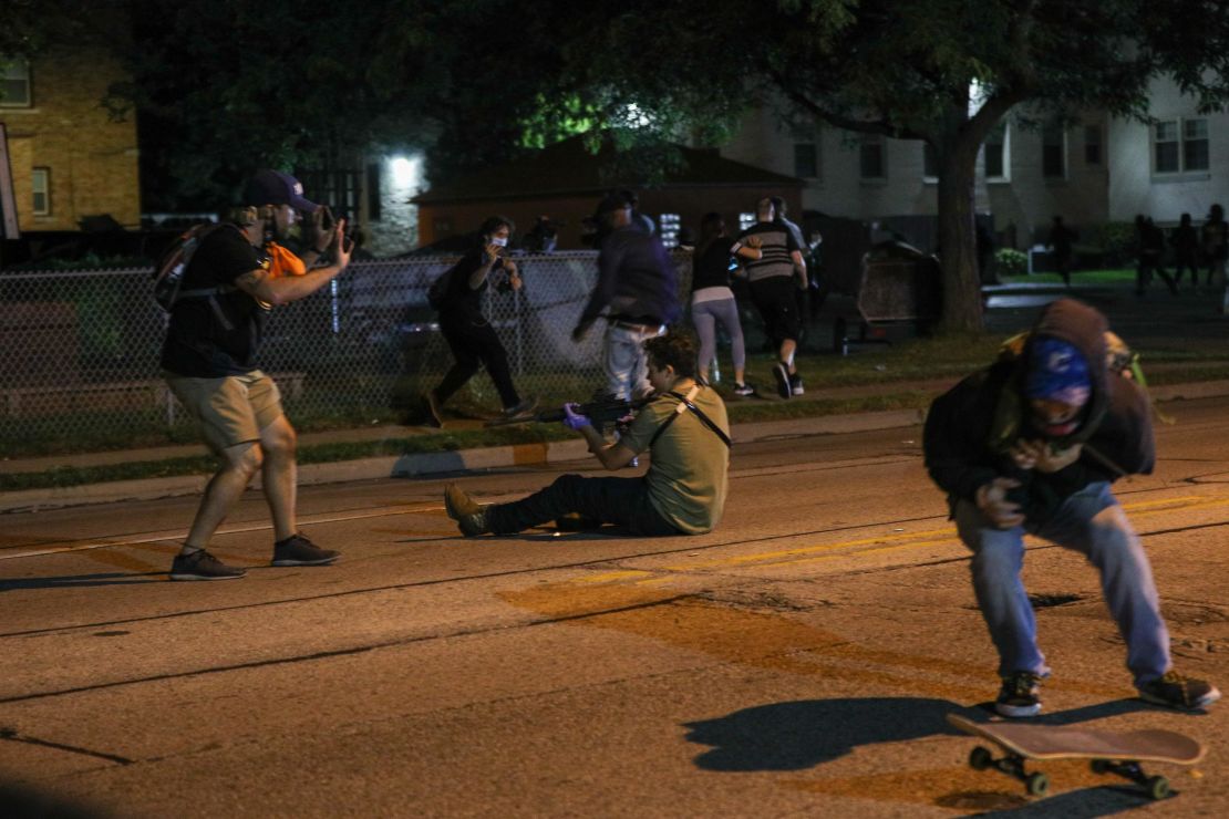 A man with a gun takes aim at another person during a third night of protests in Kenosha.