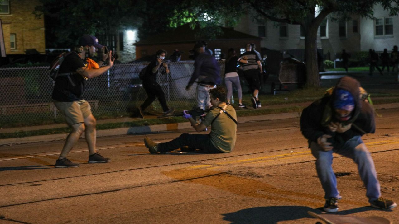 A man with a gun takes aim at another person during a third night of protests in Kenosha.