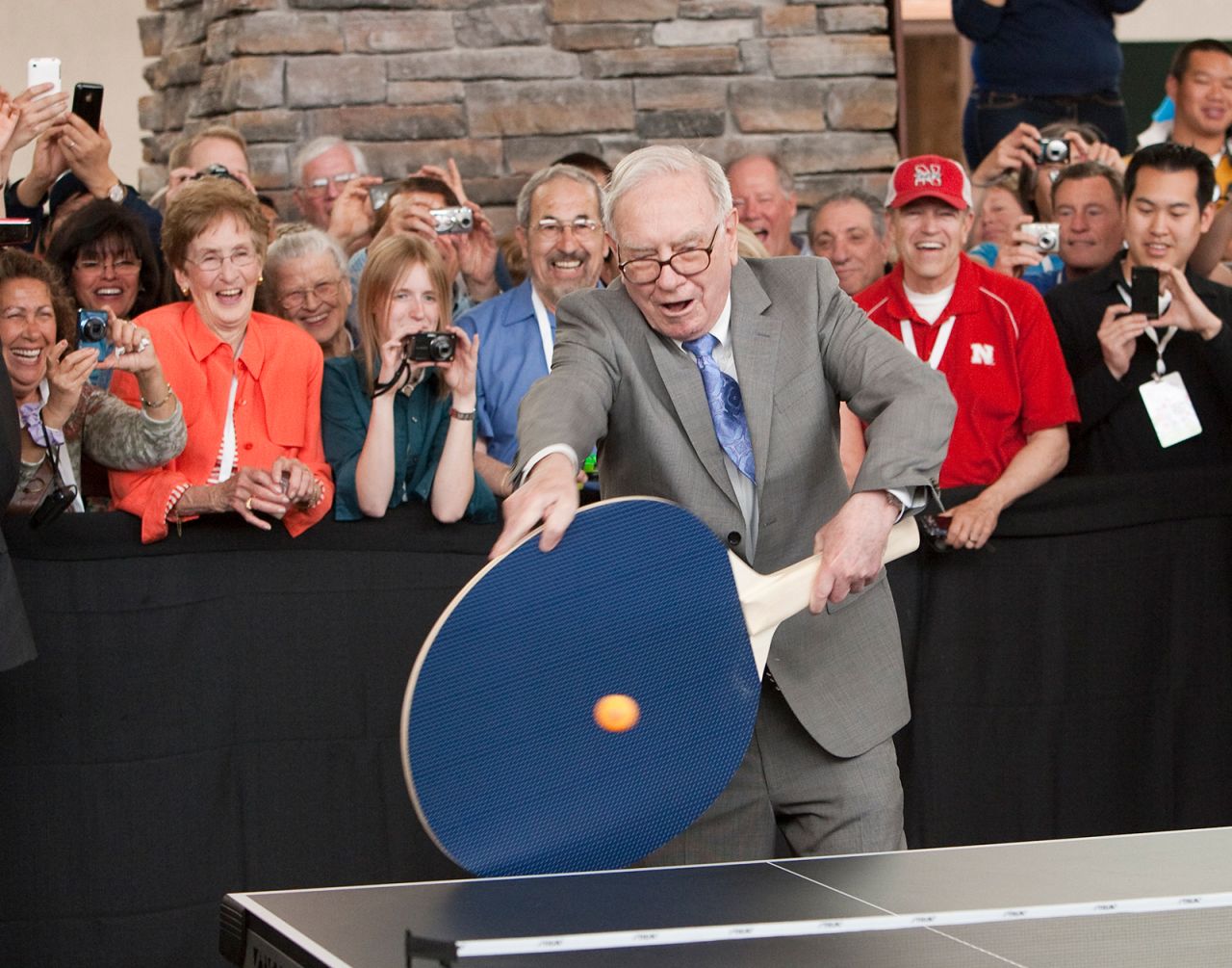 Buffett uses a large paddle to play table tennis in 2010.