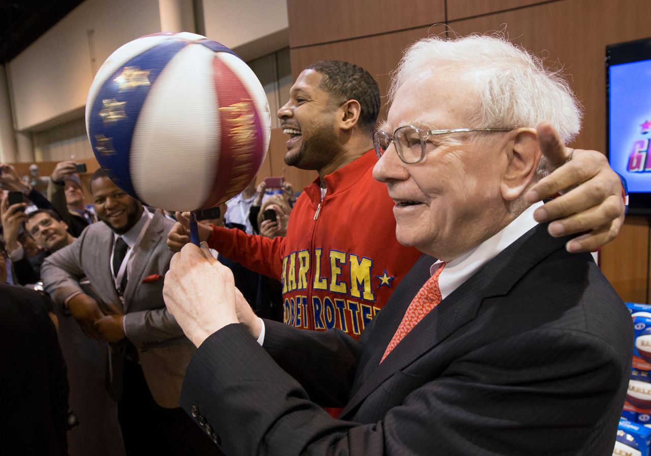 Buffett spins a basketball with the help of Chris "Handles" Franklin, one of the Harlem Globetrotters, at the Berkshire Hathaway shareholders meeting in 2013. At left is football star Ndamukong Suh.