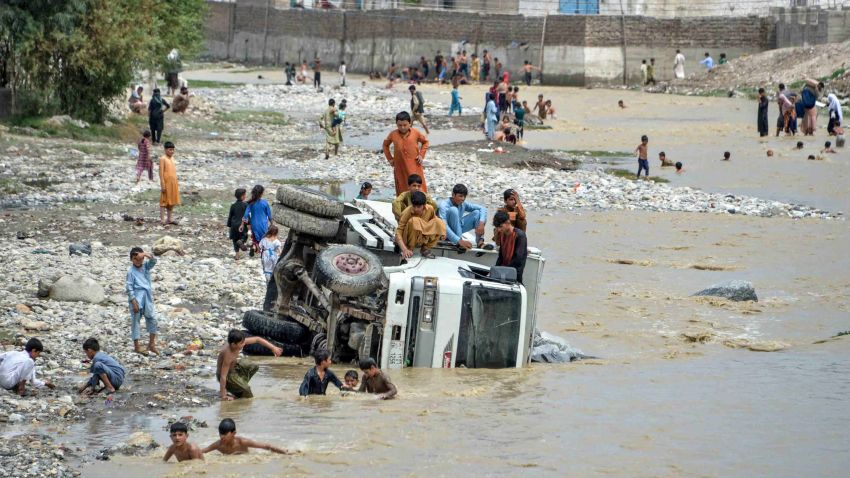 TOPSHOT - Youths sit on an overturned vehicle after flash floods triggered by heavy rainfalls affected the area in Jalalabad on August 26, 2020. - Rescue workers in Afghanistan searched on August 26 for survivors of flash floods that killed at least 100 people and destroyed hundreds of houses in a city north of Kabul, officials said. (Photo by NOORULLAH SHIRZADA / AFP) (Photo by NOORULLAH SHIRZADA/AFP via Getty Images)