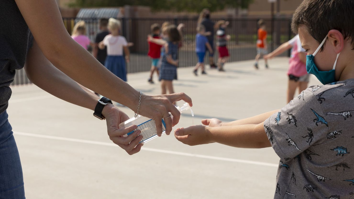 A teacher sprays hand sanitizer on a student's hands at an elementary school in Surprise, Arizona, on Aug. 20, 2020. The FDA is warning consumers about misleading packaging of hand sanitizers that look like food or drink.