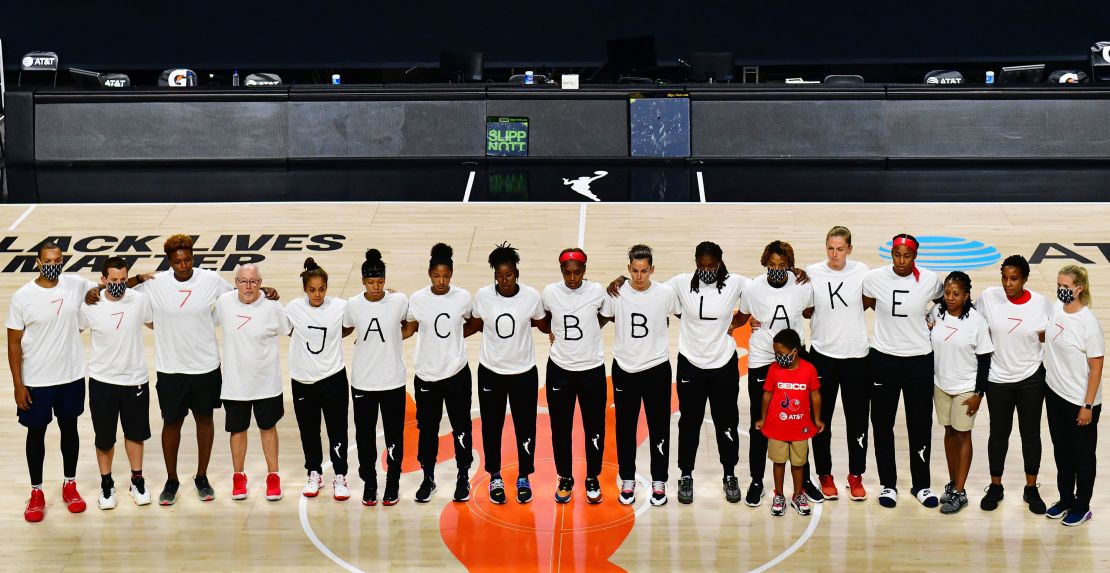 After the WNBA announcement of the postponed games for the evening, the Washington Mystics each wear white T-shirts with seven bullets on the back protesting the shooting of Jacob Blake.
