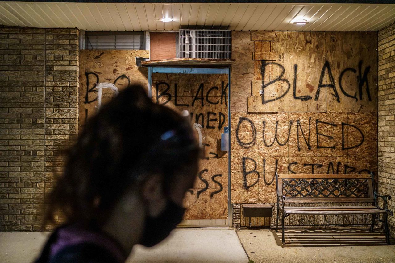 A protester walks by a boarded-up store in Kenosha on August 26.