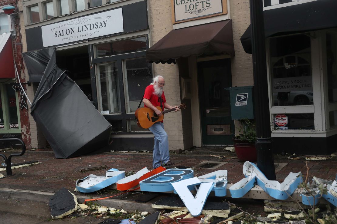 A man plays his guitar while walking through the downtown area of Lake Charles on Thursday.